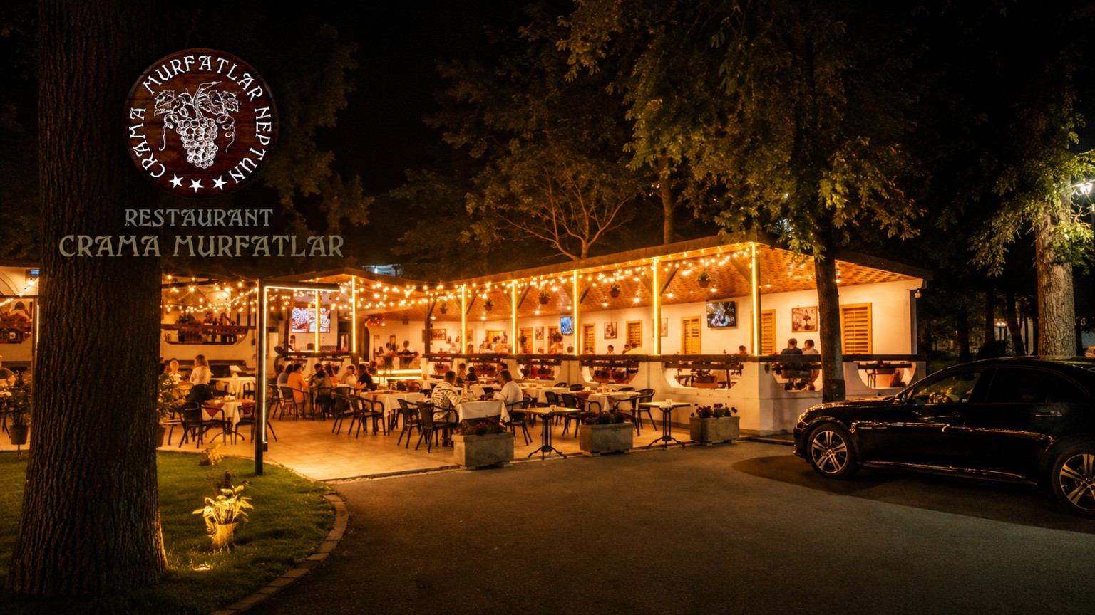 Terasa și fațada restaurantului iluminate, văzute dinspre stradă